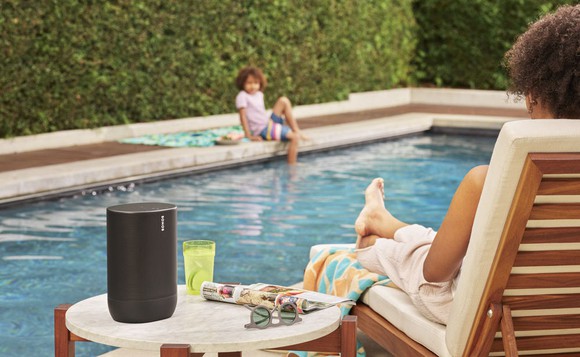 Two people listening to a Sonos Move speaker by a pool.