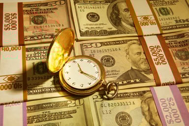 A pocket watch on a pile of cash.