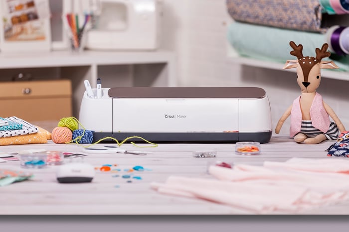 Cricut Maker surrounding by crafting supplies.