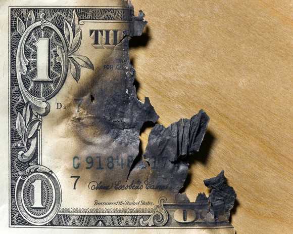 A dollar bill charred and burned down to only a portion left.
