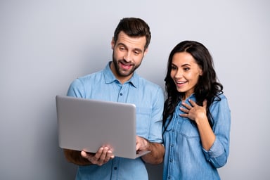 Man and woman smiling while looking at laptop