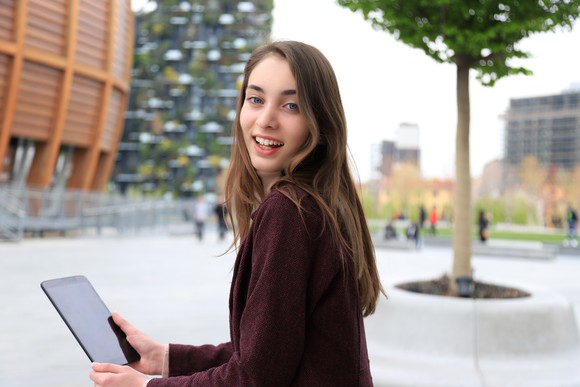 Using a tablet in front of a university building. 