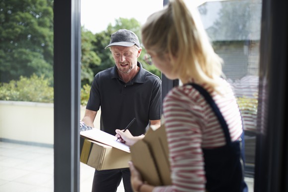 A delivery driver drops off a box at a customer's door.