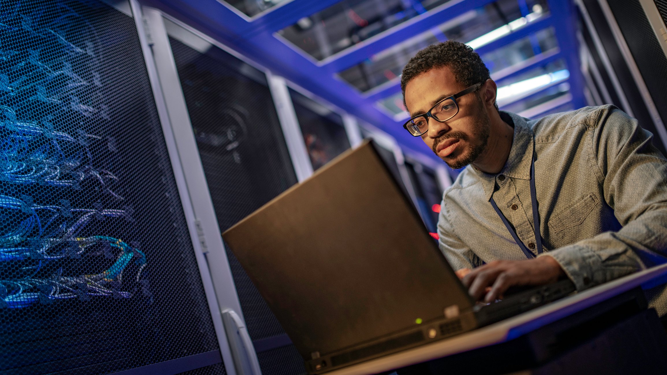 A data center worker works at a laptop. 