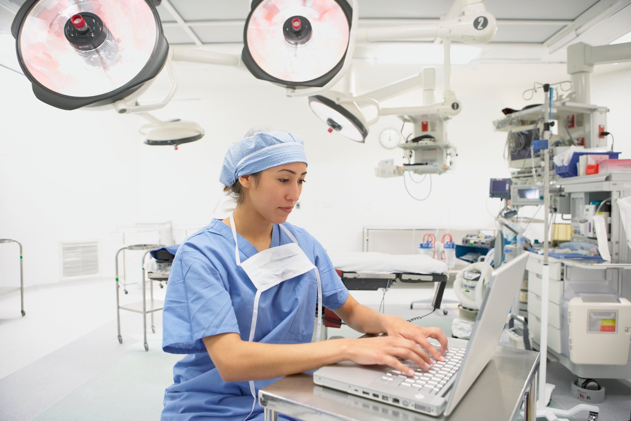 Physician typing on laptop in an operating room. 