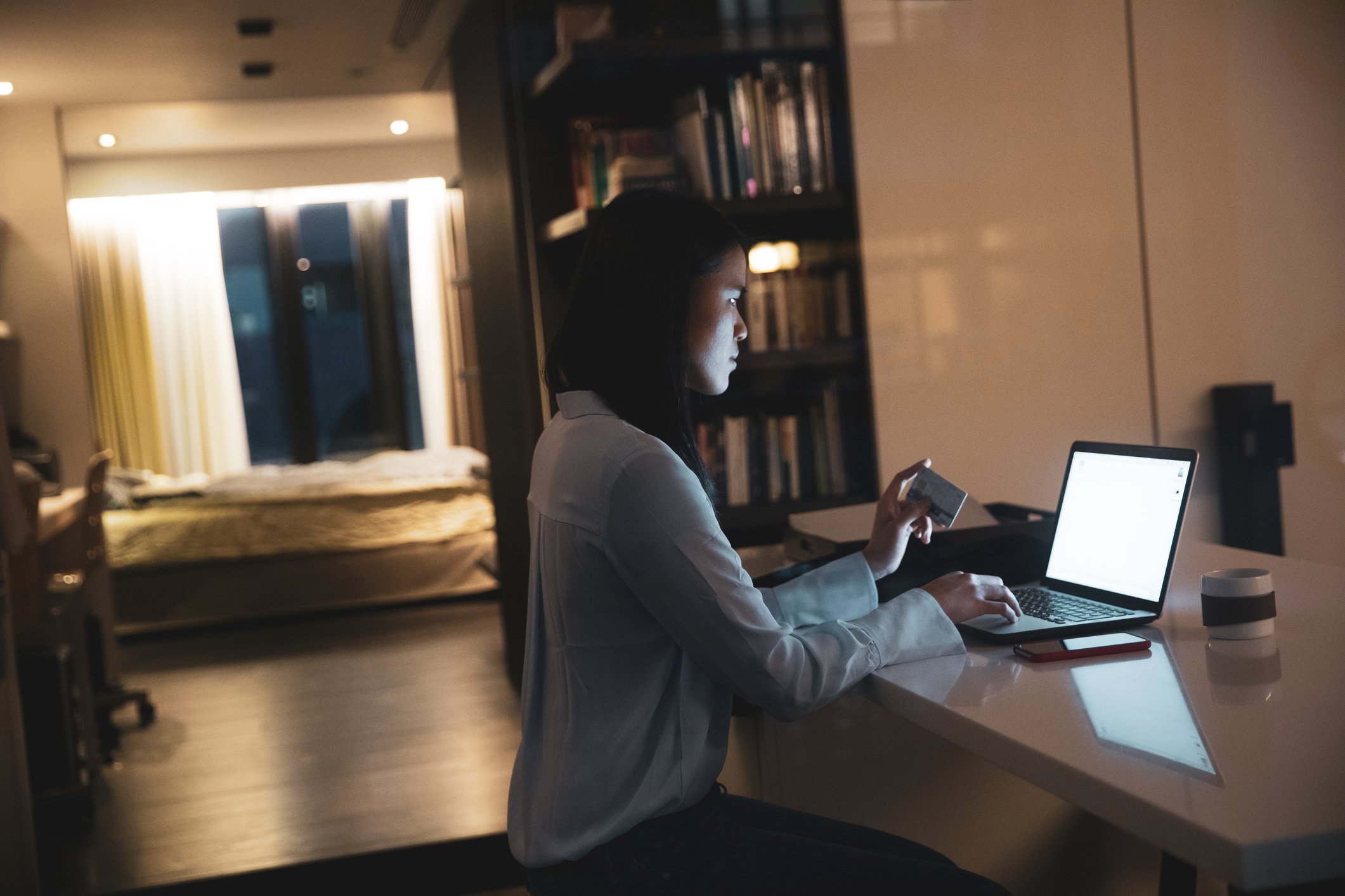 A person is holding a credit card while sitting in front of a computer. 