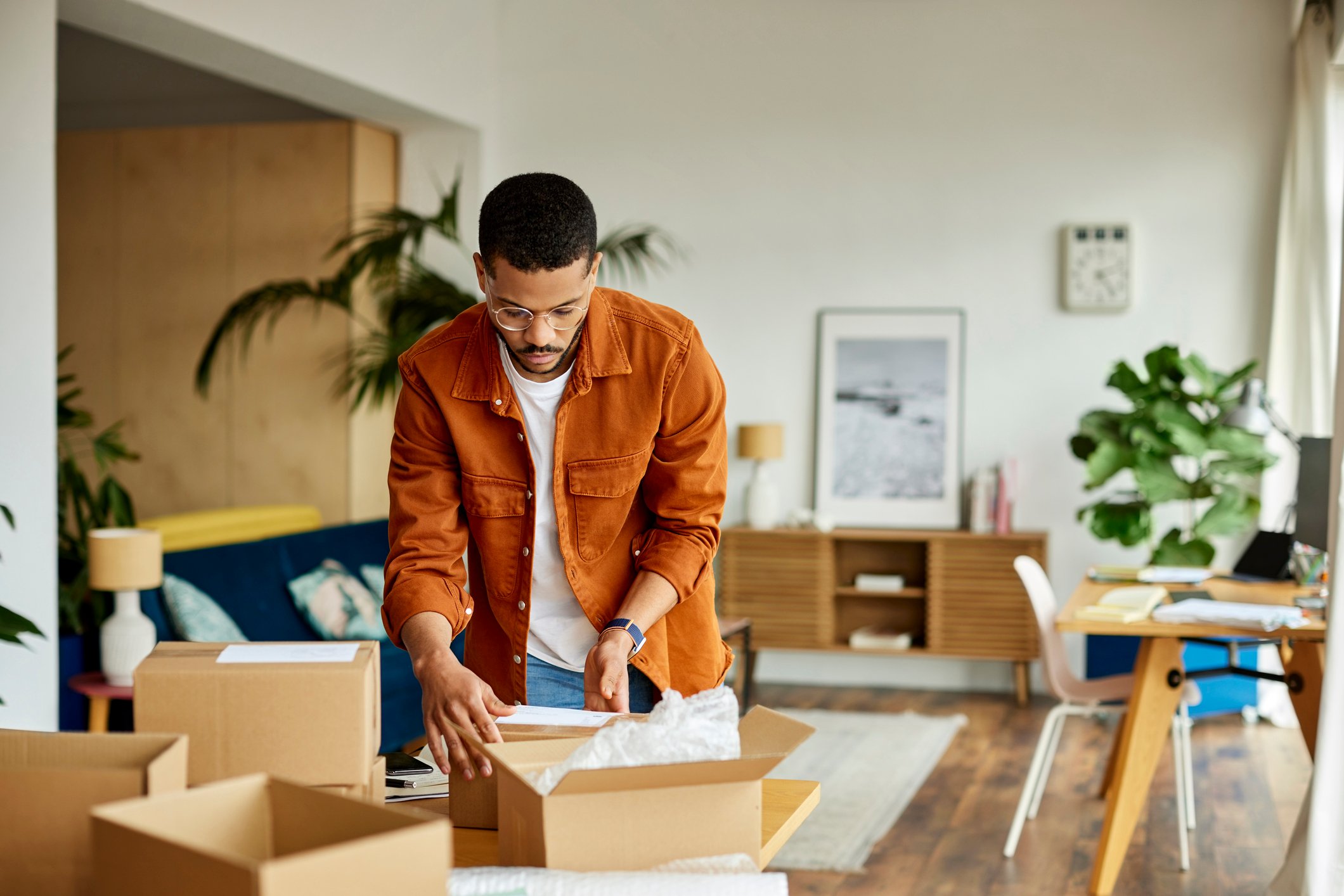 A person looking at boxes in a living room.