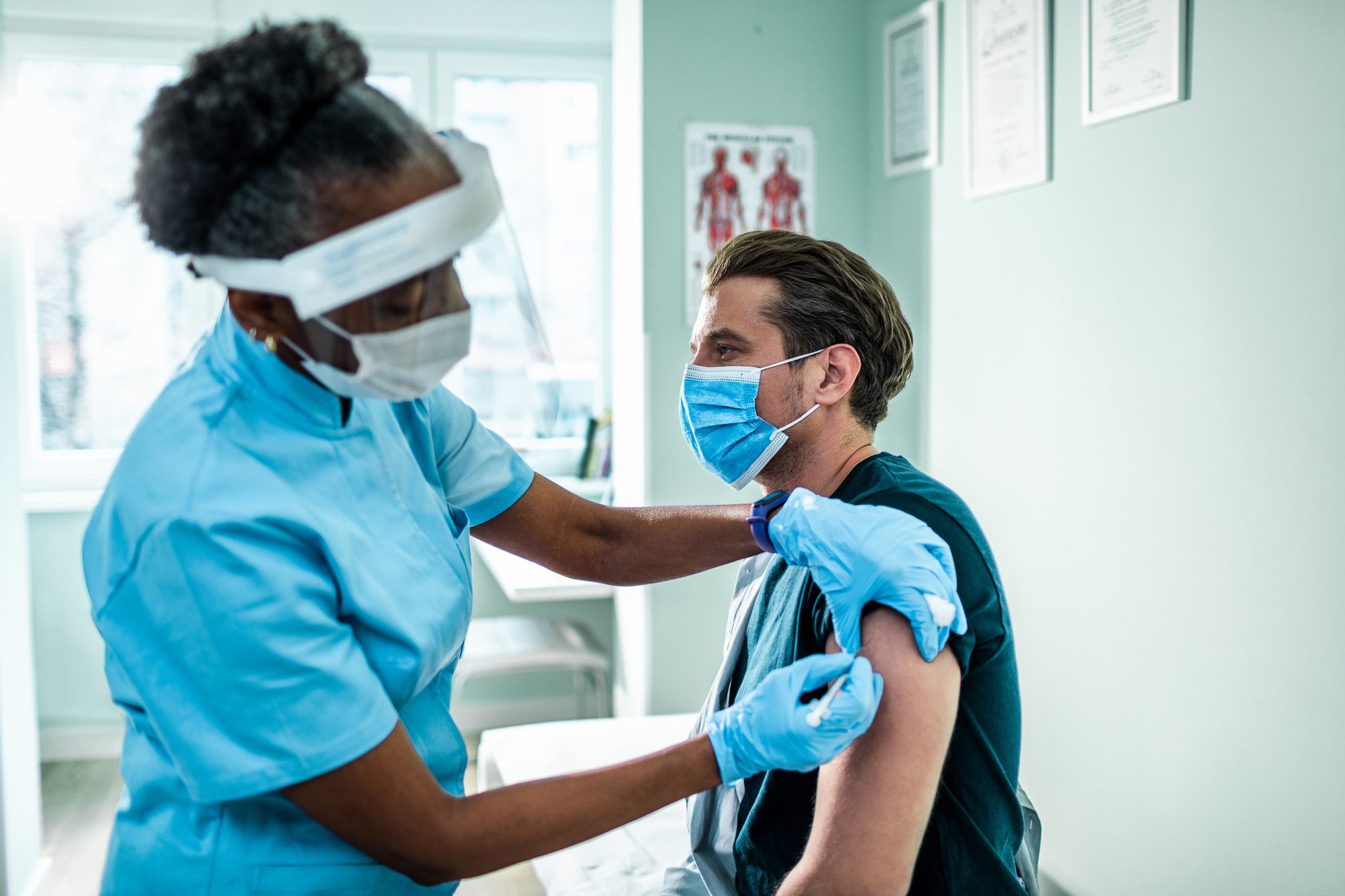 A man getting a vaccine from a female health worker.