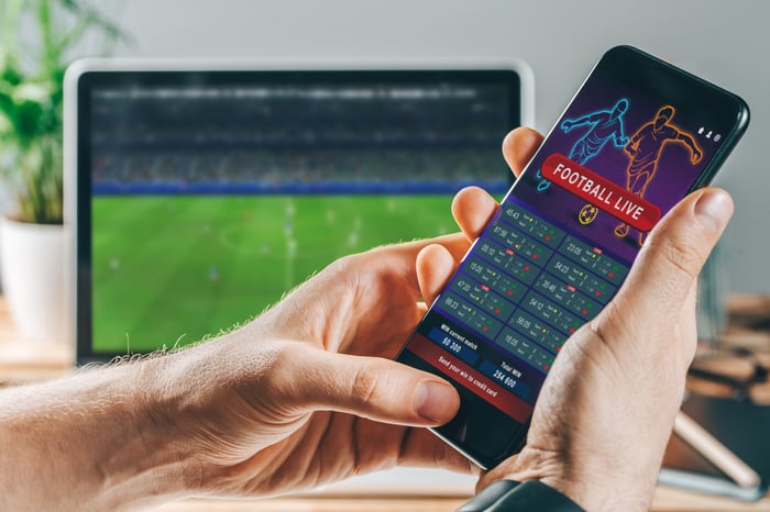 Two hands holding a smartphone with a sports betting app.