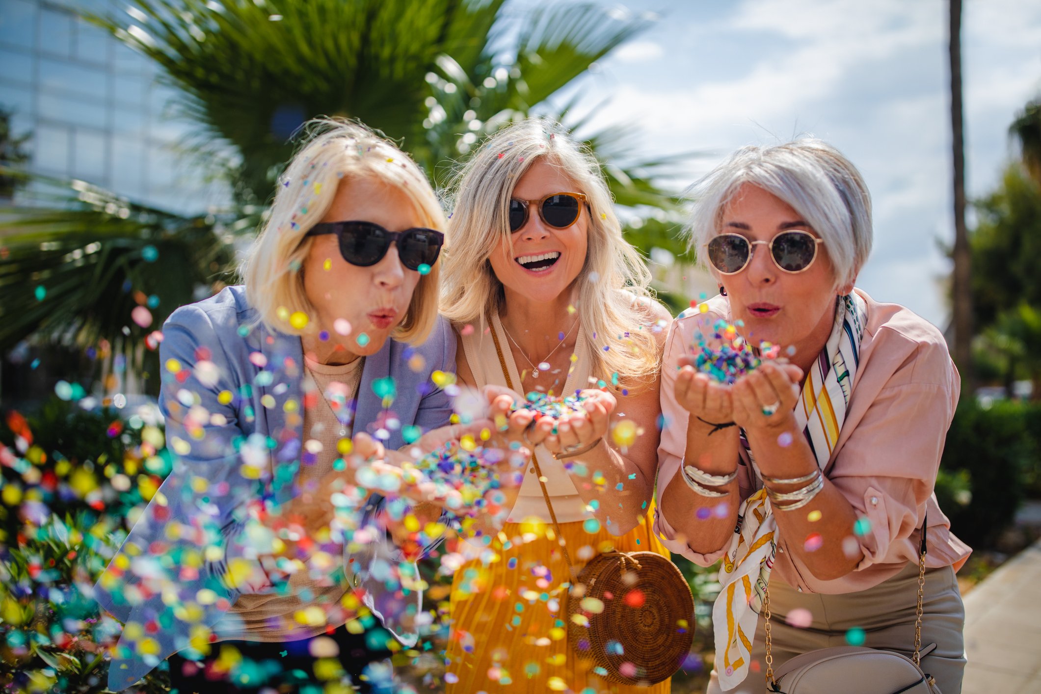 Three seniors blowing confetti out of their hands.