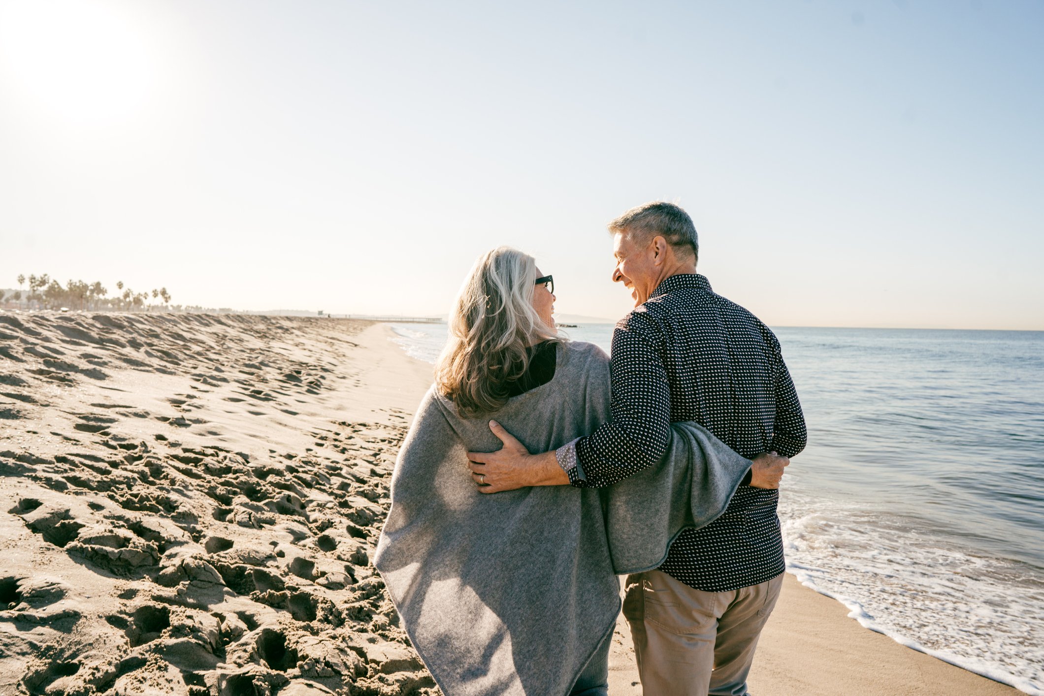 Two elderly people walking at the beach.