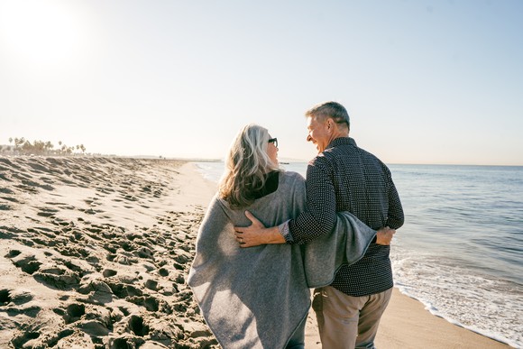 Two elderly people walking at the beach.