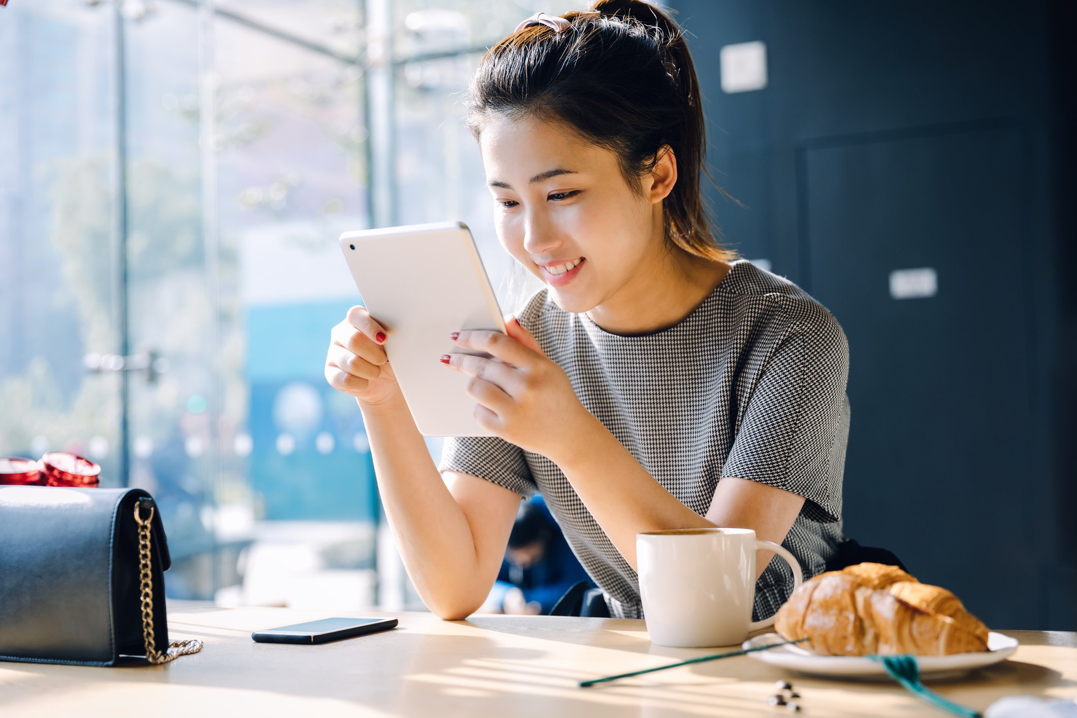 A person reads a tablet while eating breakfast.