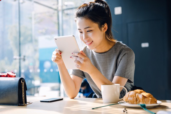 A person reads a tablet while eating breakfast.