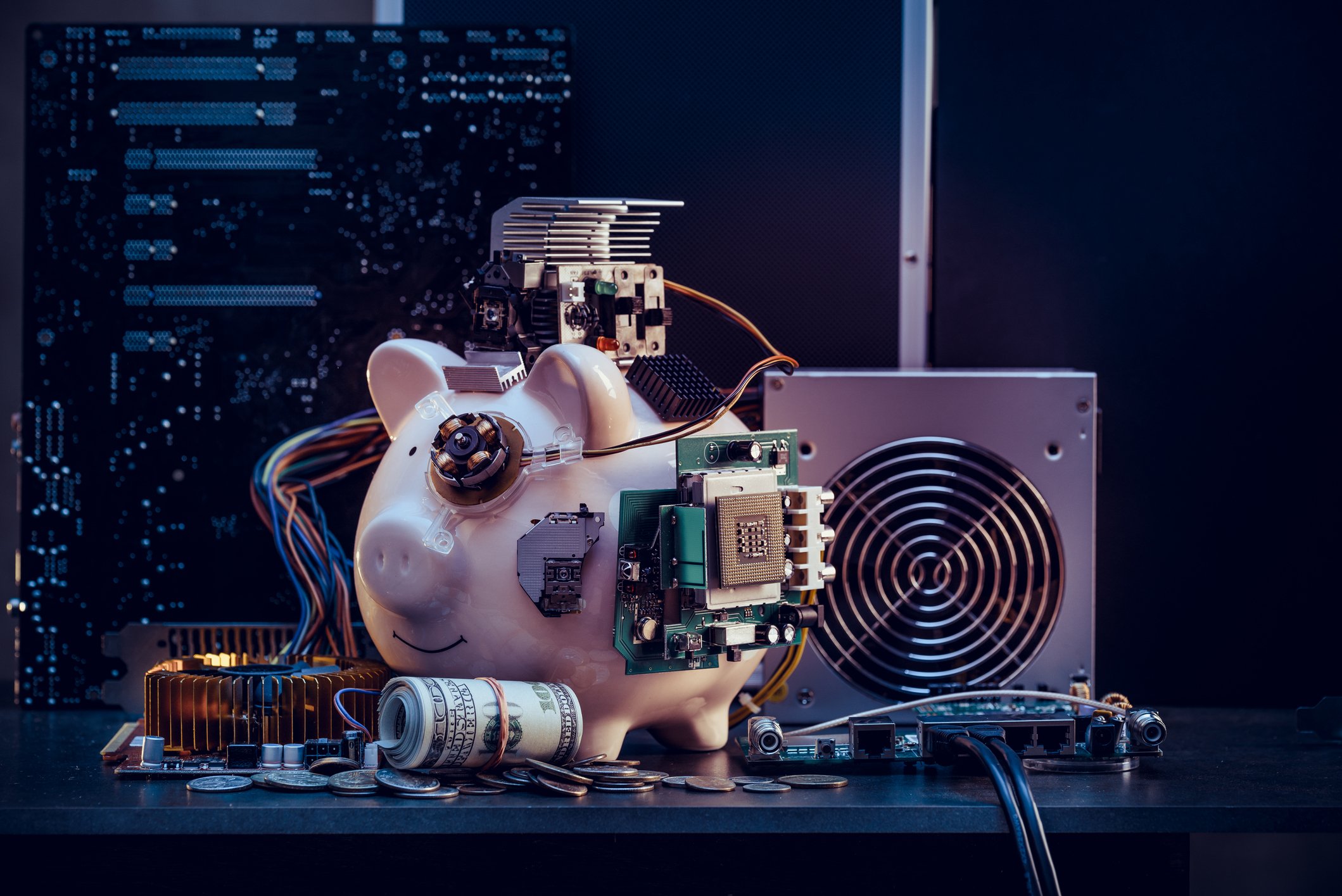 Piggy bank connected to mining hardware along with a roll of money.