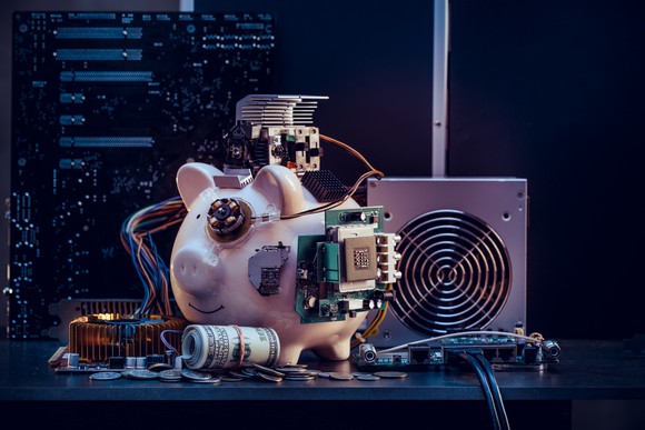 Piggy bank connected to mining hardware along with a roll of money.