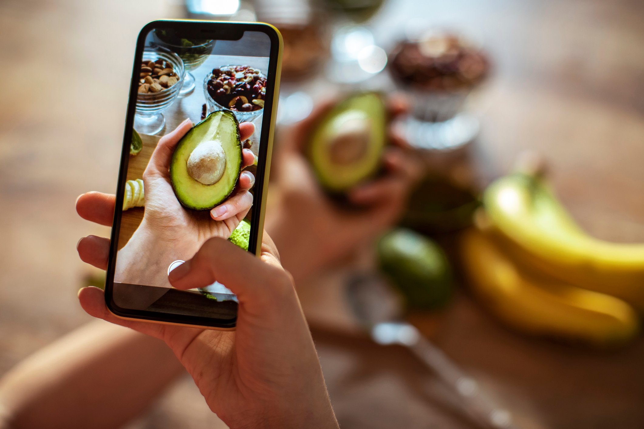 A person holding an avocado and taking a photo of it.