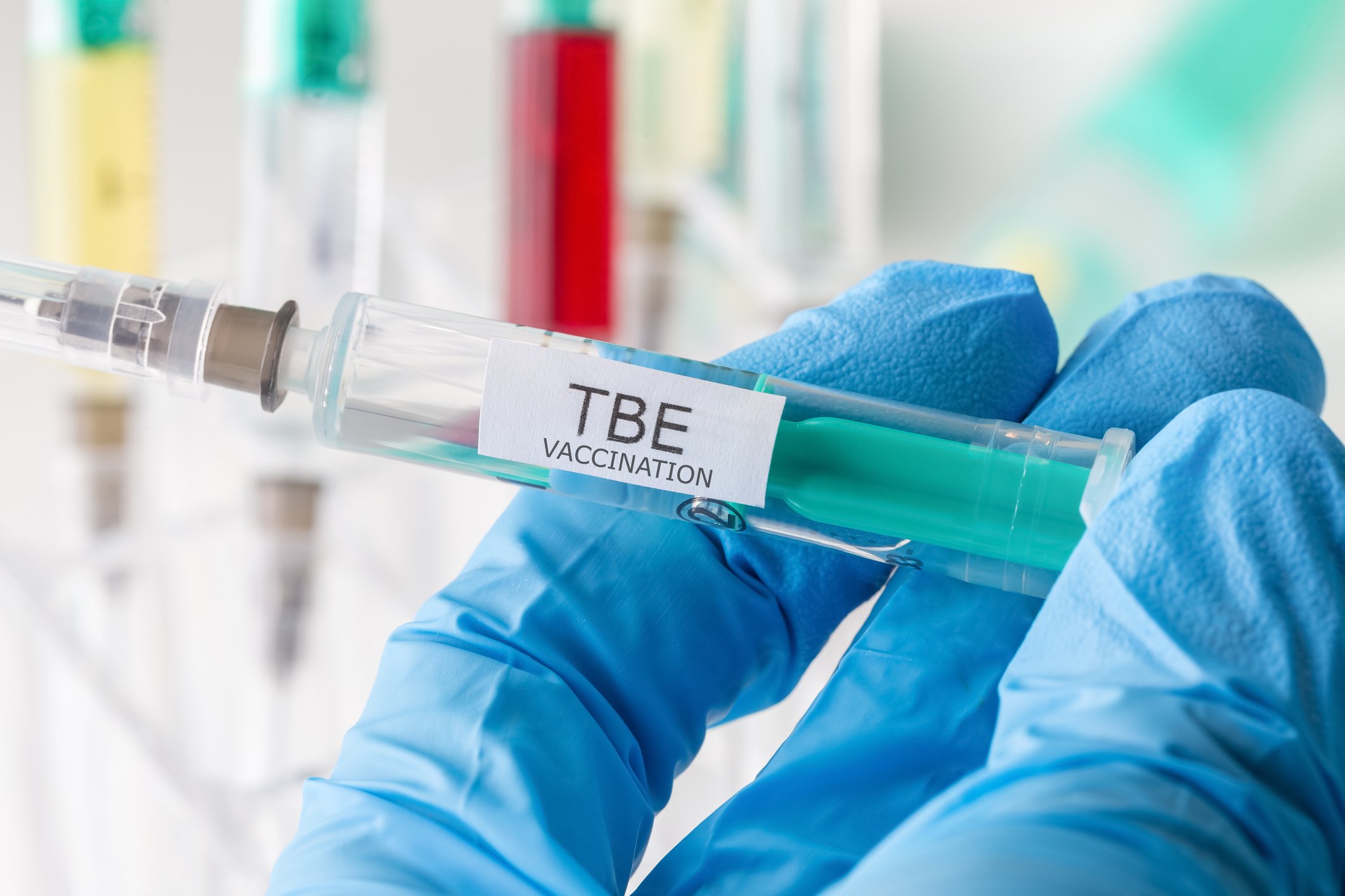 A gloved hand holds a tick-borne encephalitis vaccine.