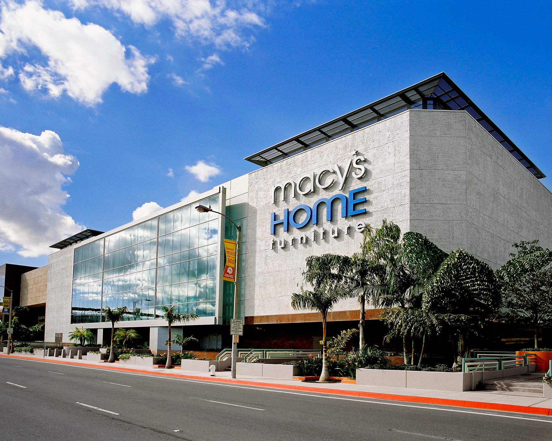 The sunlit front of the Macy's store in Costa Mesa, CA, under a blue sky.