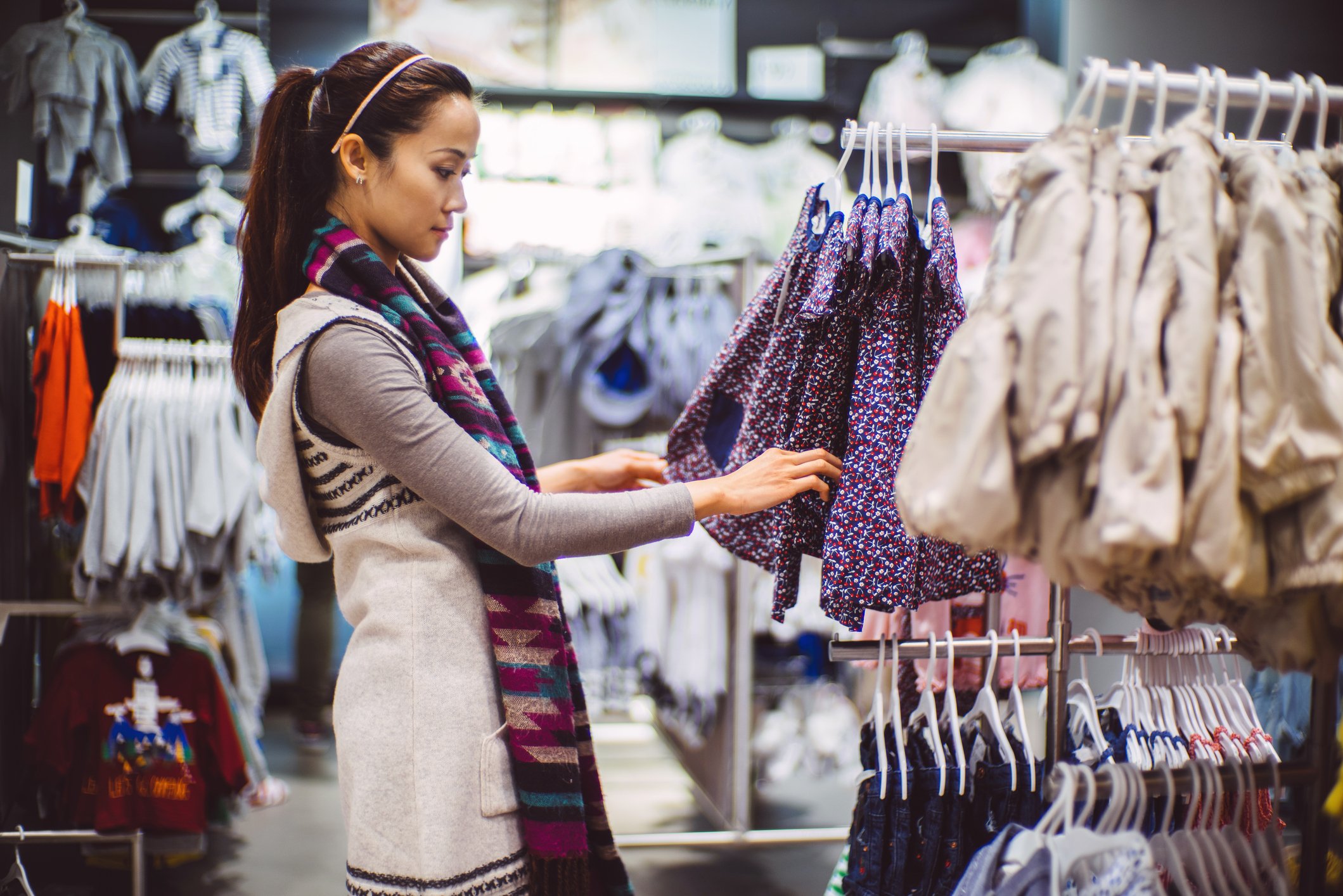 A person looking a baby clothing in a store.
