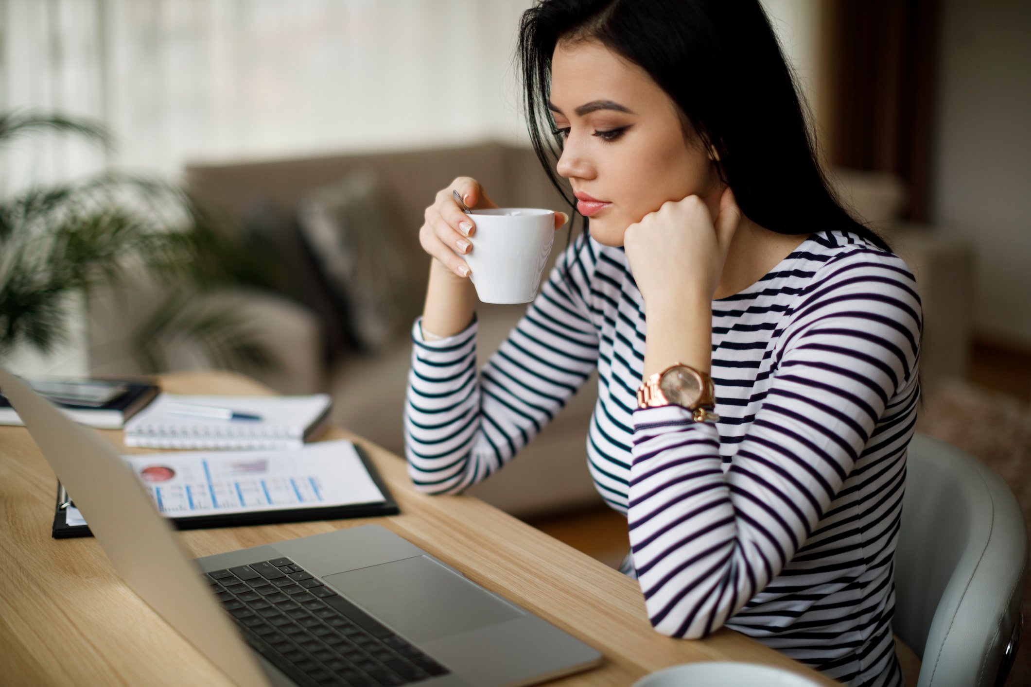 Person sipping coffee while checking their computer.