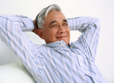 Older man smiling with hands behind his head