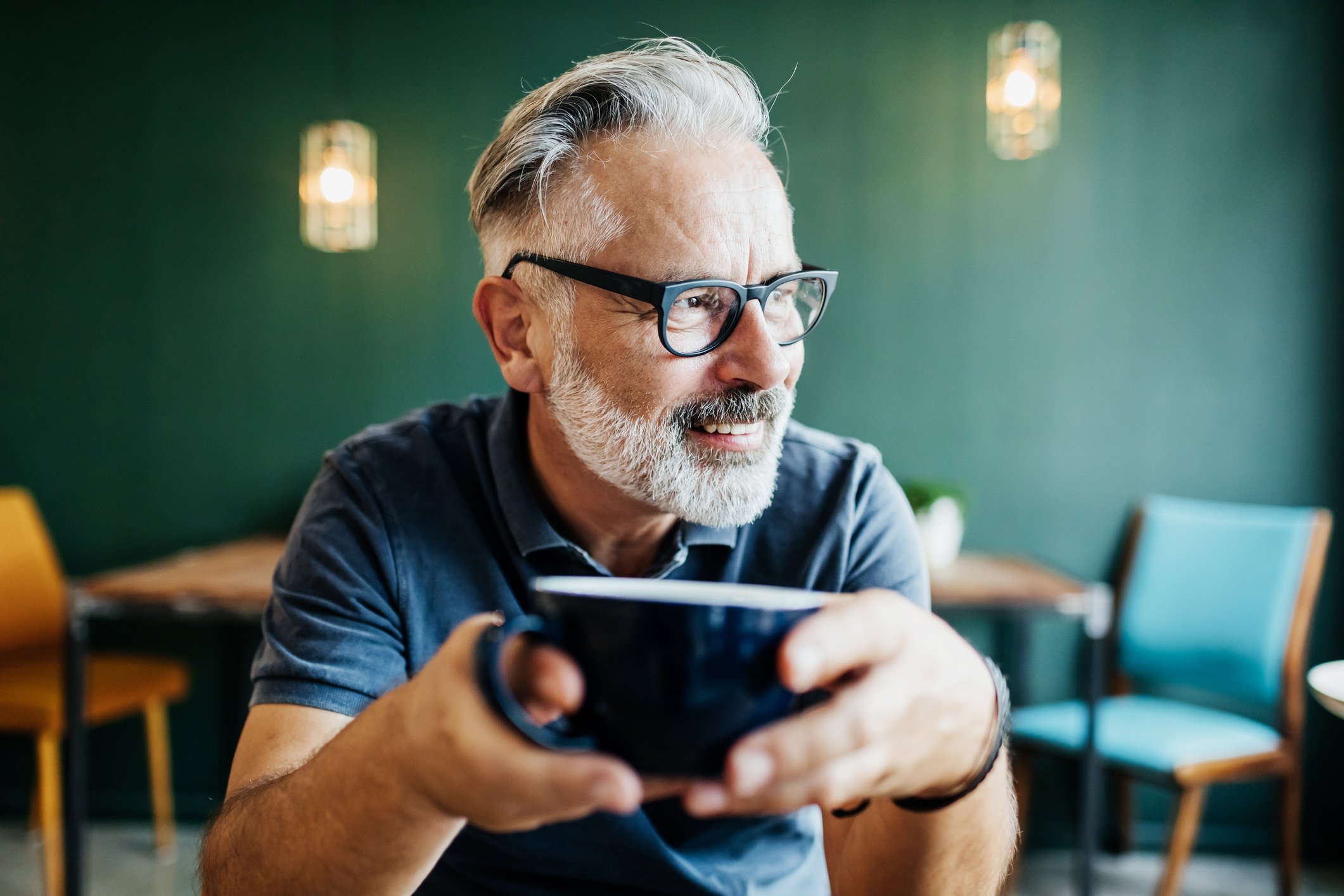 Person sitting in coffee shop holding large cup of coffee.