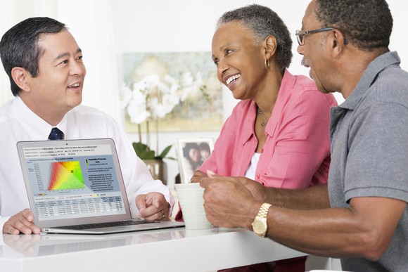 A smiling couple looking at a computer screen showing a dot in the green instead of the yellow or red.