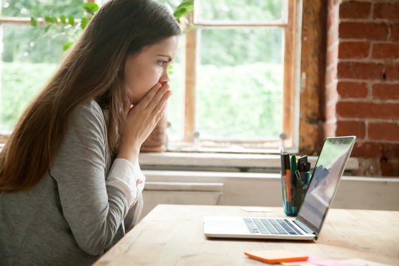 An anxious woman looking at a laptop.