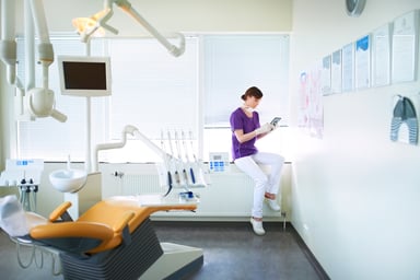 dentist looks at phone while waiting for patient