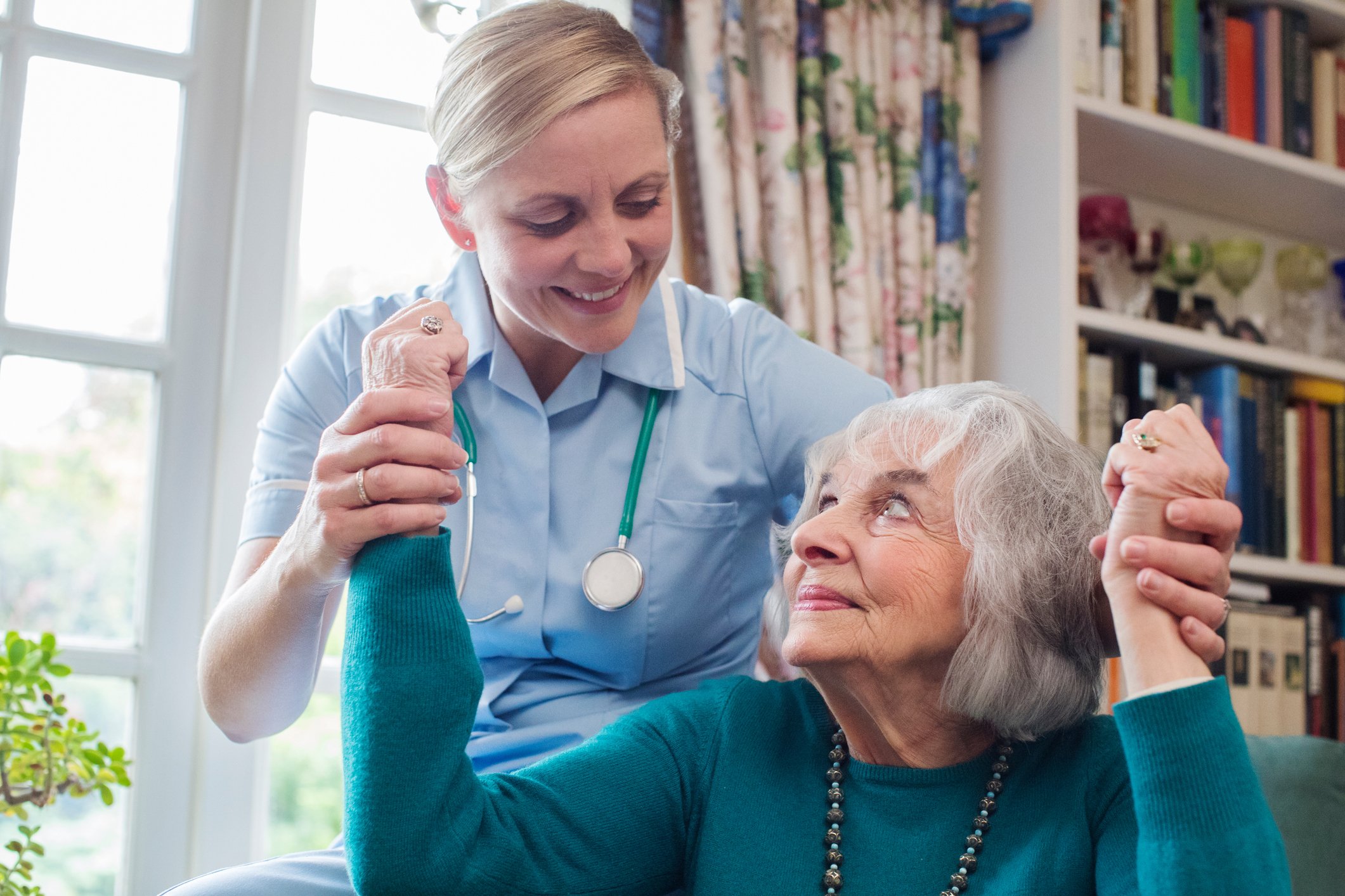 A clinician helping an elderly person raise their arms.