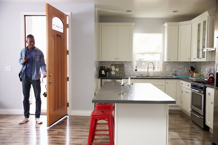 A man unlocks a door and enters an apartment.