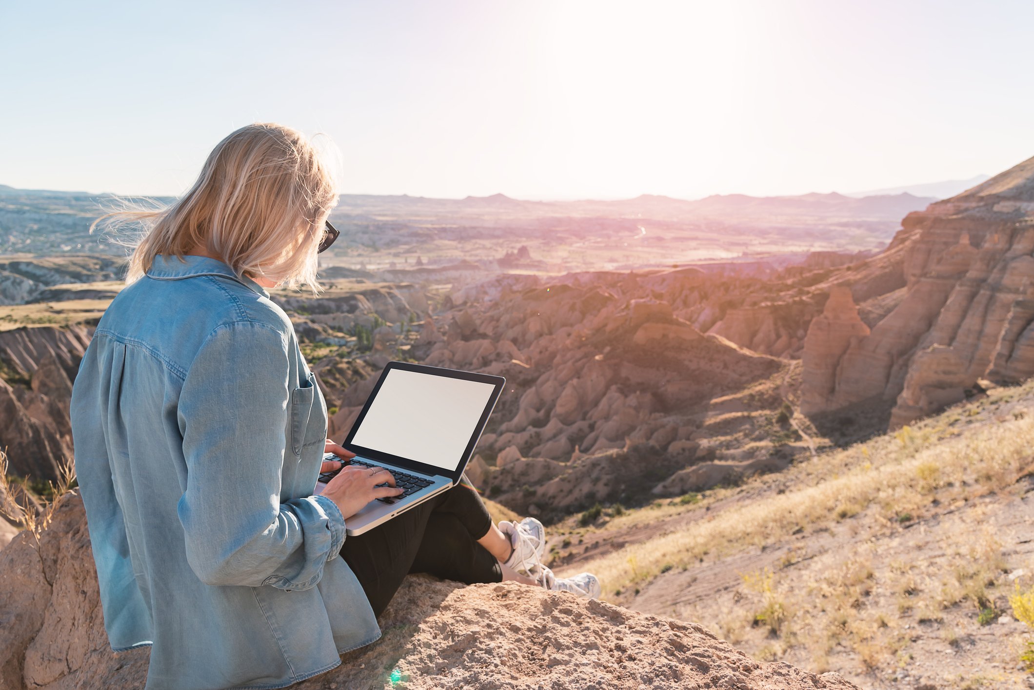 Person sitting on top of mountain using a laptop computer