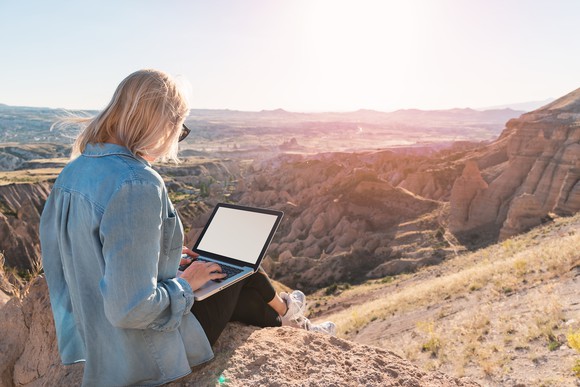 Person sitting on top of mountain using a laptop computer