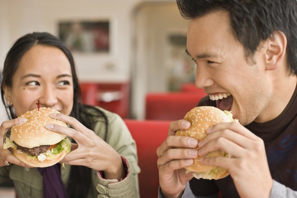 Two people about to bite into hamburgers.