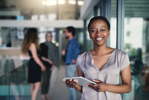 Person holding tablet in an office setting, smiling. 