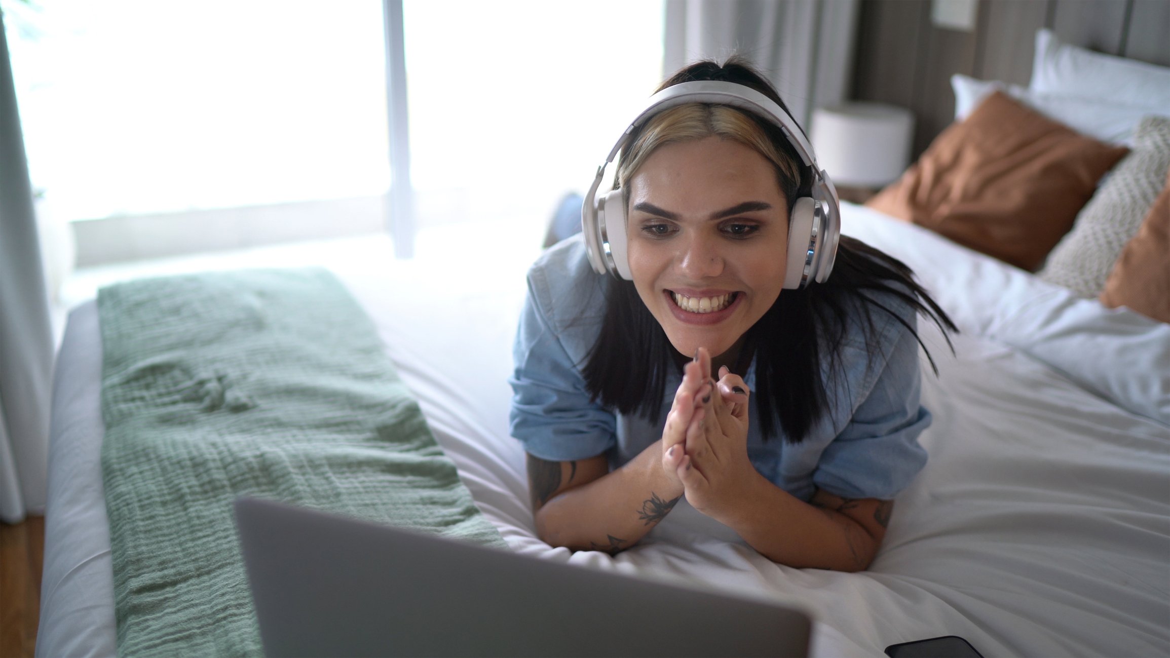 A person wearing headphones while watching something on a laptop.