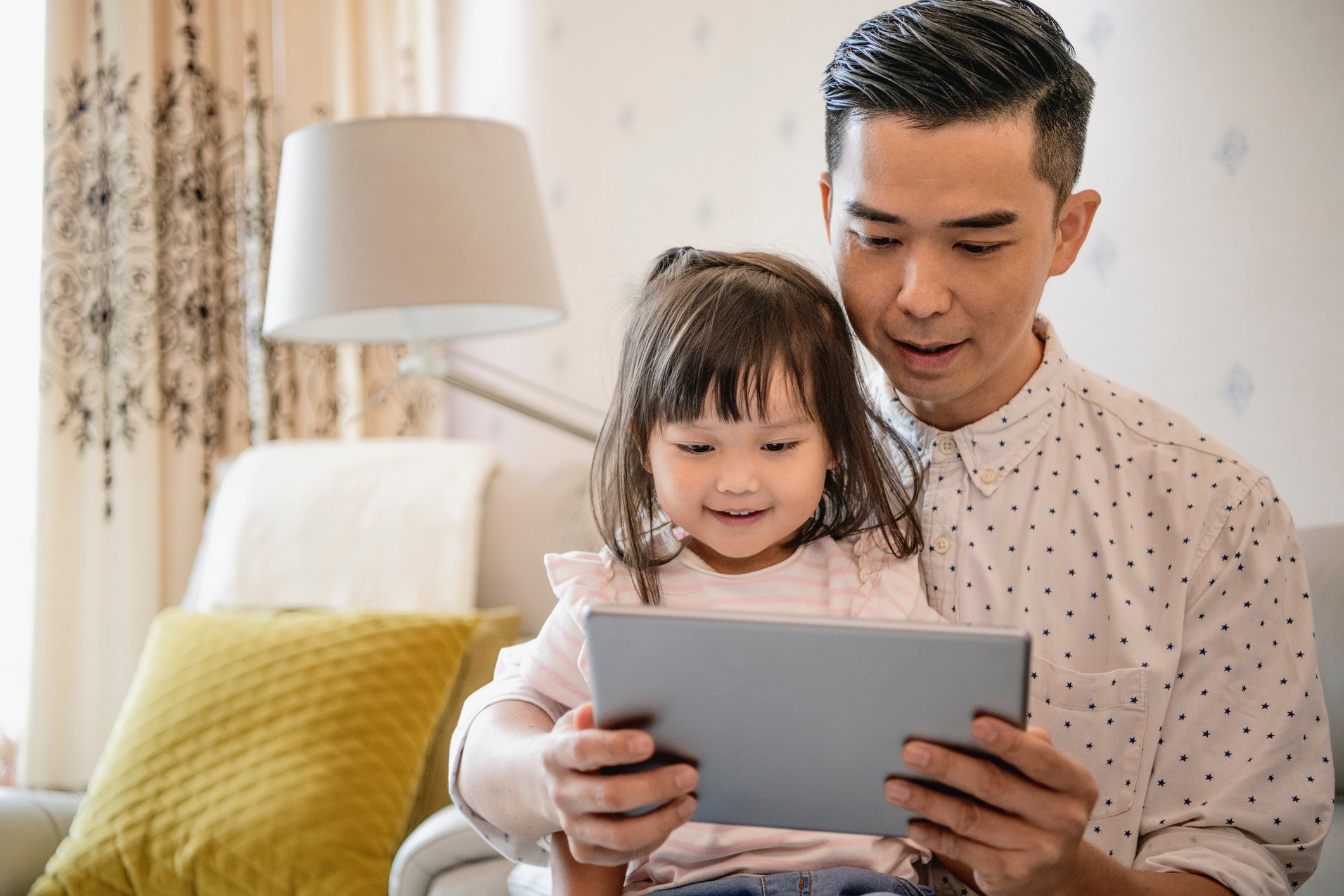 A parent and child watching a program on a tablet together.