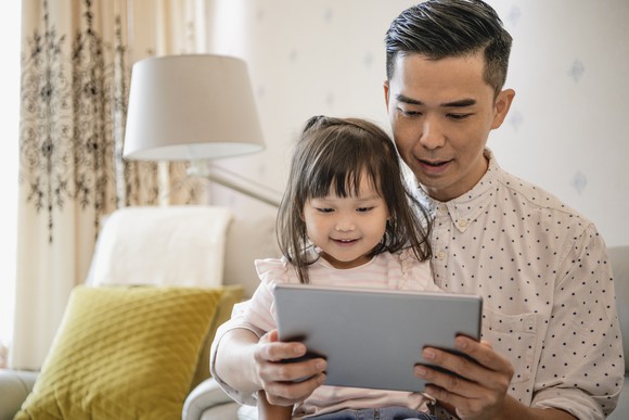 A parent and child watching a program on a tablet together.