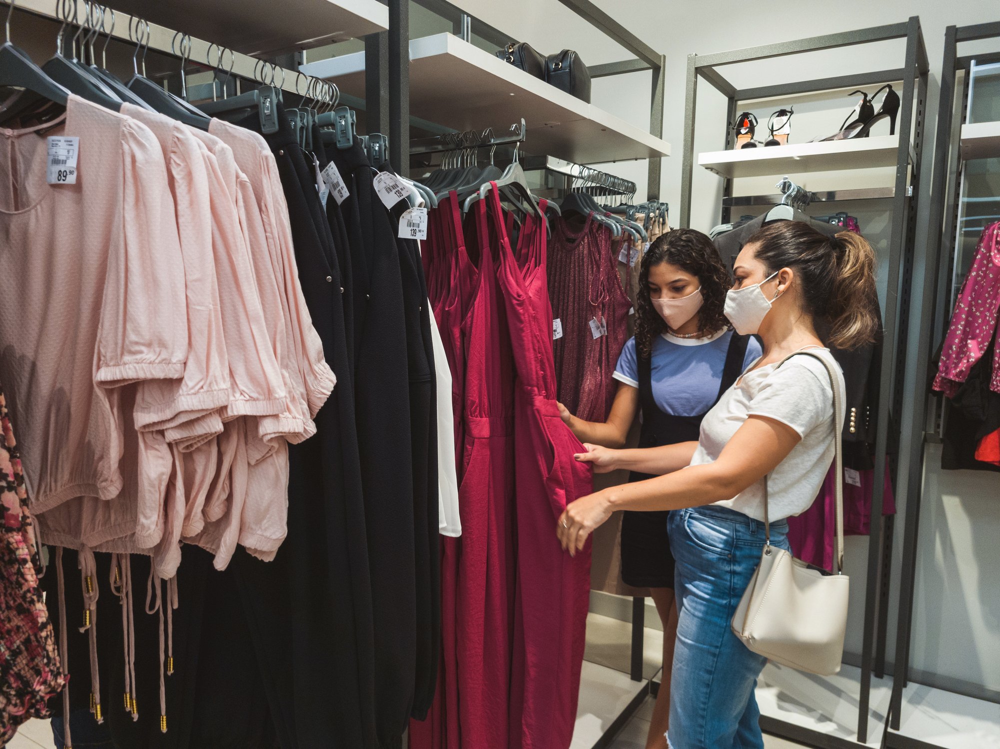 Two people at a clothing store examining a dress.