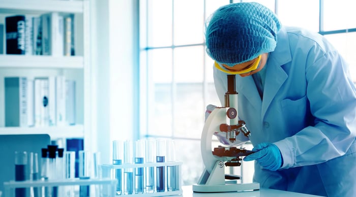 Person looking through microscope in a lab.