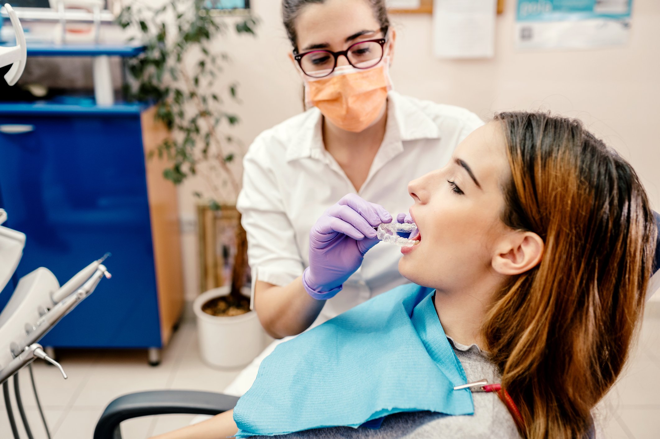 A patient in an orthodontists chair getting fitted for a clear aligner teeth straightening device.