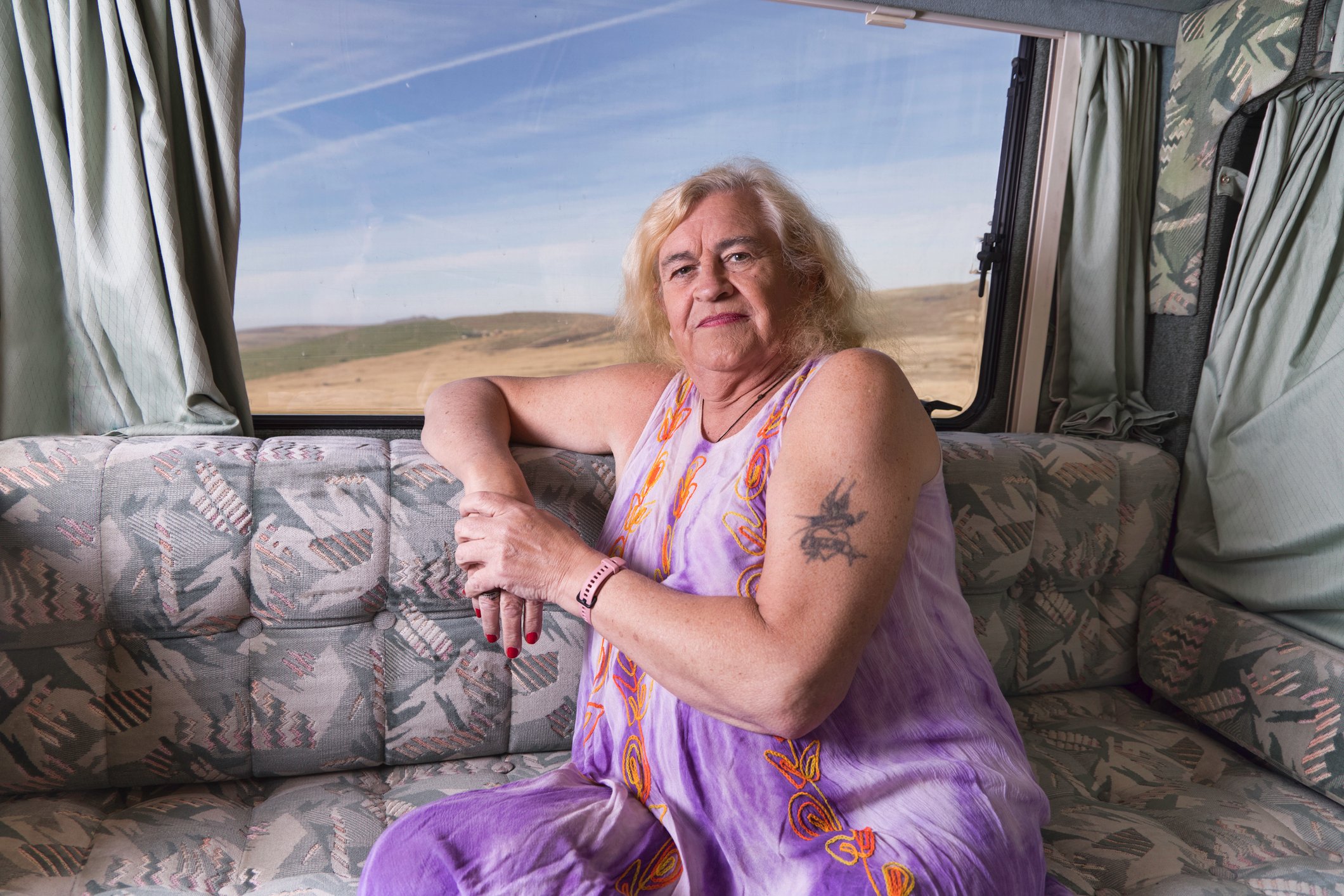 A person is looking serious, sitting on a couch in an RV.