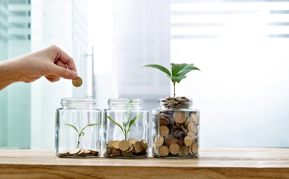 Three jars filled with coins and sprouting plants.