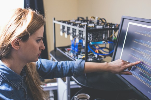 A person at their computer monitoring cryptocurrency mining equipment.