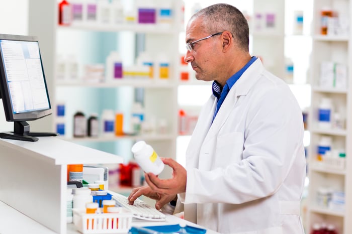 Pharmacist holding up a pill bottle.