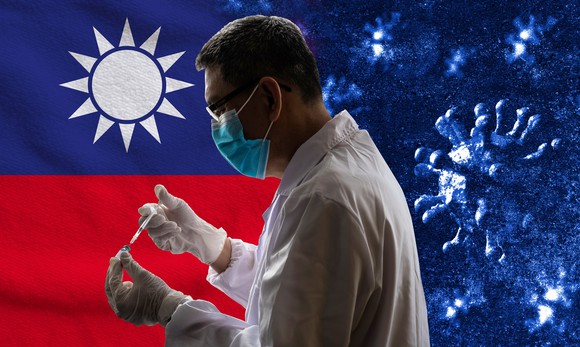 A person wearing a face mask holding a syringe and vaccine vial with a Taiwanese flag and coronavirus in the background.