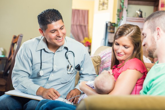 A doctor sits with a couple and their newborn.