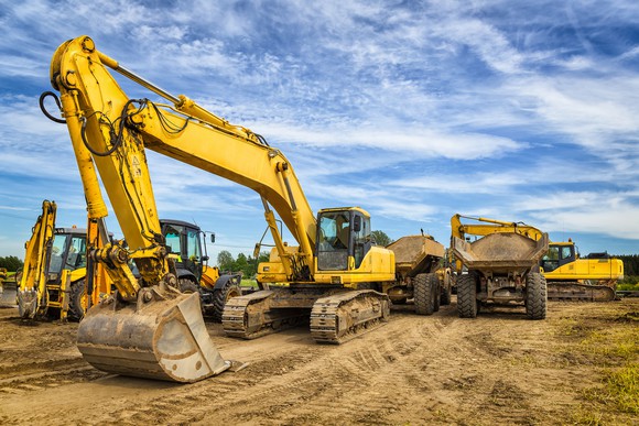 An excavator and other heavy equipment under a cirrus sky at a construction site. 