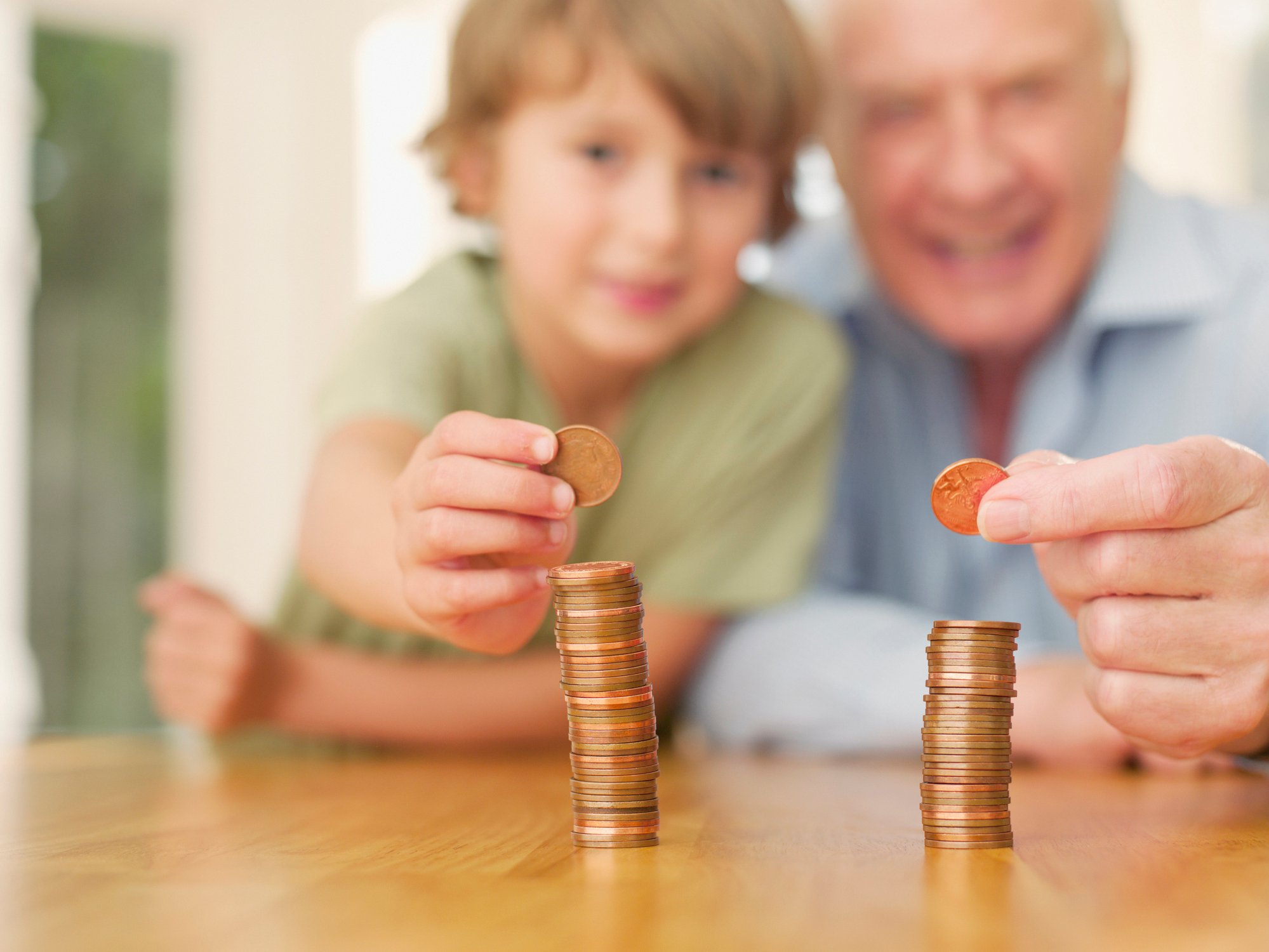 A child and grandparent each make a stack of coins on a table.